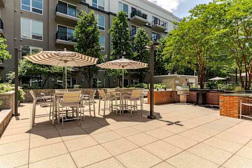 A patio with tables and chairs and umbrellas.