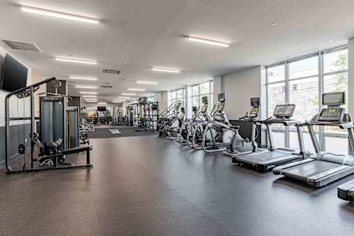 A spacious gym with a variety of equipment including treadmills, stationary bikes, and weight machines.