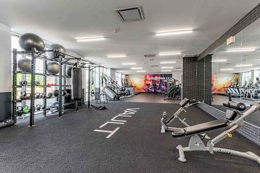 A gym with a variety of equipment including a weight bench, a squat rack, and a rowing machine.