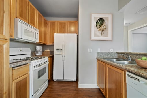 2 Bedroom Apartments in Petaluma, CA - Theatre Square - Kitchen With Light Wood-Style Cabinetry, Breakfast Bar, Granite Countertops, White Appliances, And Wood-Plank Flooring