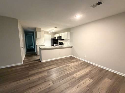 A room with wooden flooring and white walls.