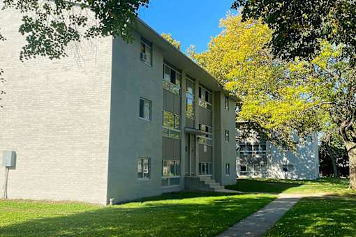 A grey building with a tree in front.