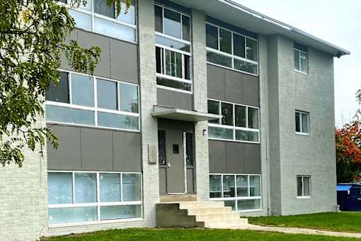A grey and white building with a front door and steps.