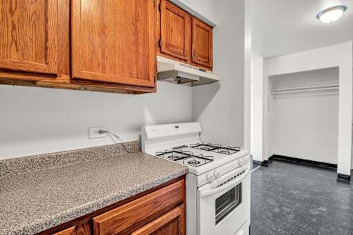 A kitchen with a white stove and wooden cabinets.