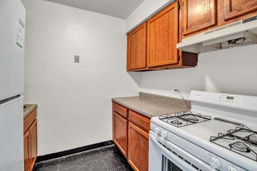 A kitchen with a white stove and wooden cabinets.
