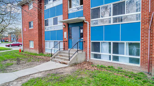 A red car is parked on the street in front of a building.