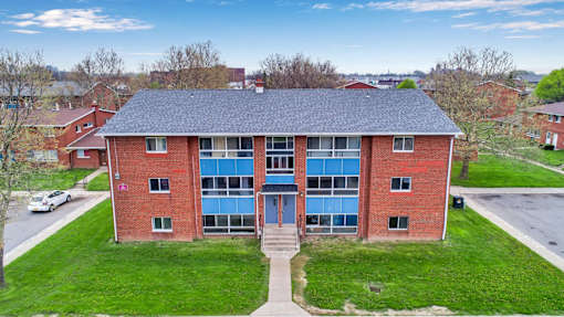 A red brick building with a blue roof and a white car parked in front.