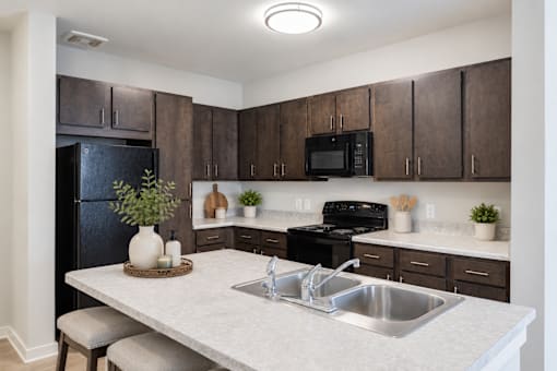 Professionally staged kitchen with breakfast bar at Townes at Clarkston Centre apartments in Clarkston, GA.