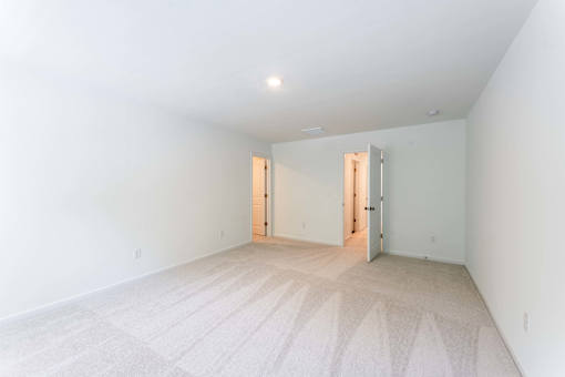 Spacious carpeted bedroom with neutral walls and bright lighting at Townes at Olde Birch townhomes in Raleigh, NC.
