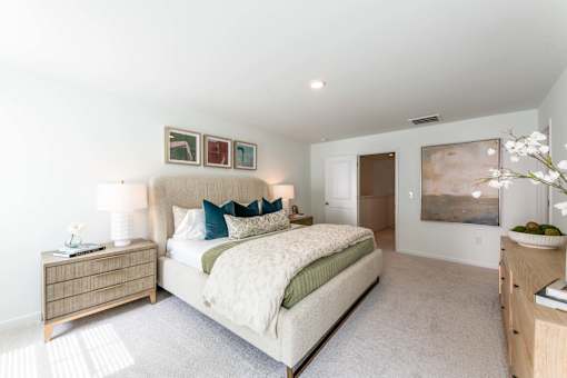 Large primary bedroom with carpet flooring, neutral finishes, modern furniture, and natural light at Townes at Olde Birch in Raleigh, NC.