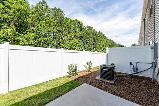 Private fenced backyard patio with green lawn, concrete patio space, and wooded views at Townes at Olde Birch townhomes in Raleigh, NC.
