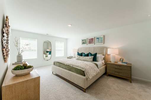 Spacious model townhome bedroom with carpet flooring, large windows, neutral finishes, and modern bedroom furniture at Townes at Olde Birch in Raleigh, NC.
