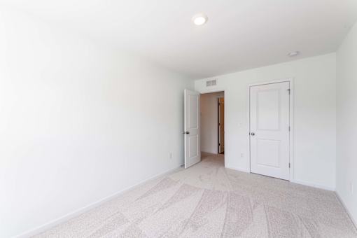 Unfurnished third bedroom with carpet flooring, neutral walls, closet door, and flexible layout at Townes at Olde Birch in Raleigh, NC.
