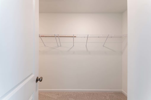 Spacious walk-in closet with wire shelving and carpet flooring inside a townhome bedroom at Townes at Olde Birch in Raleigh, NC.