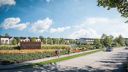A sign for Townhomes is in front of a building and some trees.