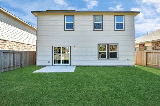 4 Bedroom Single Family Homes for Rent in Houston TX - Imperial Forest - Back of a Home Exterior, with White Walls, Windows, Sliding Glass Back Door, and Grassy Lawns in a Fenced-In Yard