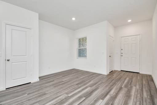 A room with white walls and wooden flooring with two doors.