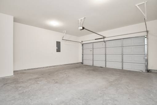 A large empty garage with a white door and a grey floor.
