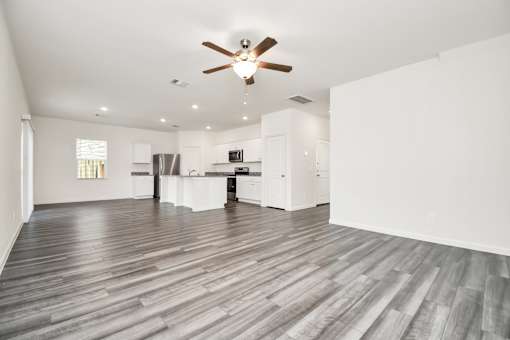 A spacious room with a ceiling fan and wooden flooring.