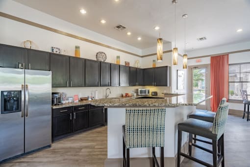 a kitchen with black cabinets and a bar with two stools
