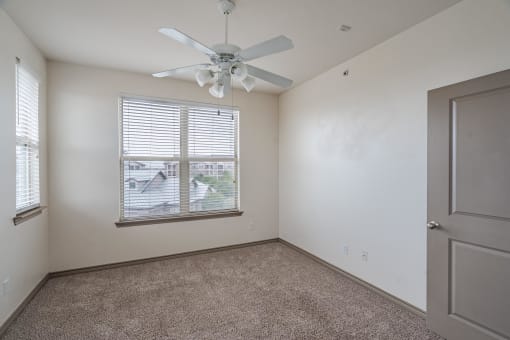 an empty bedroom with a ceiling fan and a window