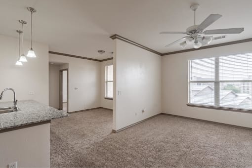 an empty living room with a ceiling fan and a window