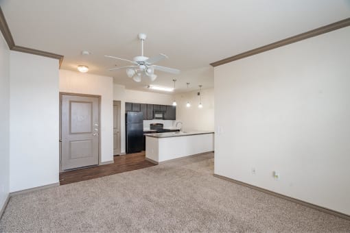 an empty living room and kitchen with a ceiling fan