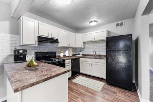 Overland Park, KS Apartments – Treetop Lodge – A kitchen with black appliances and white cabinets.