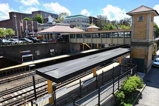 A train station with a black roof and a yellow fence.