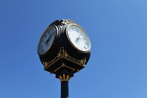 A clock tower with two clocks on top of a black pole.