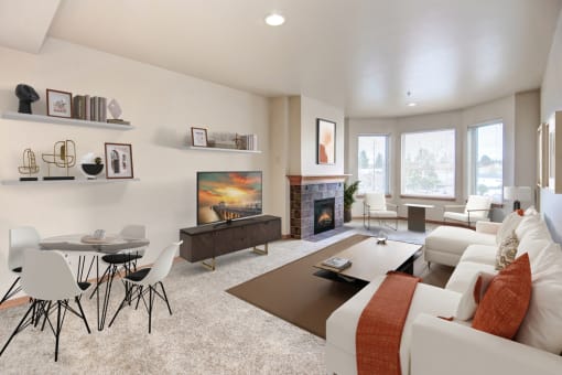 a living room with white couches and chairs and a coffee table in front of a fireplace