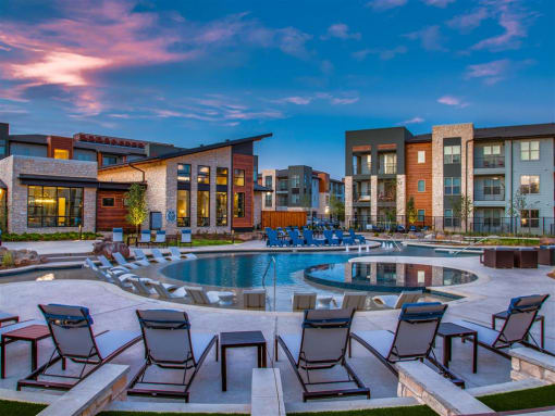 Apartments for Rent Grand Prairie - Large Sparkling Pool at Dusk Surrounded by Poolside Lounge Chairs