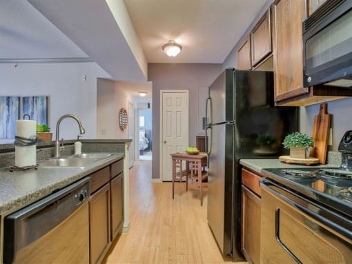 Kitchen with ceiling light, stainless steel appliances, dishwasher, oven, stove top, microwave, wood floor and wood cabinets