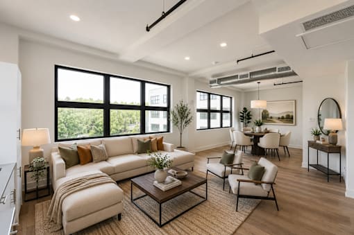 A well-lit, modern living room with a large window and a variety of furniture.
