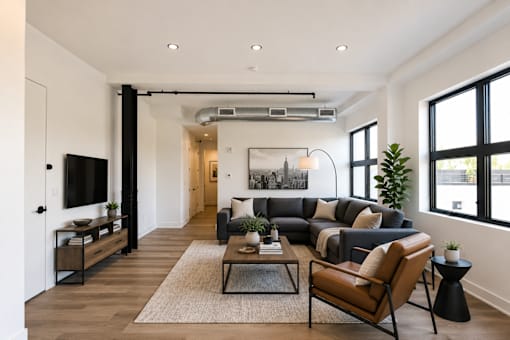 A modern living room with a large couch, a coffee table, and a flat-screen TV.