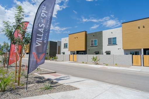 A row of modern townhouses with a banner that reads "VILLAS AT 91ST REM".