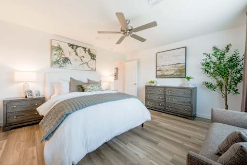 A bedroom with a large bed, a dresser, and a ceiling fan.