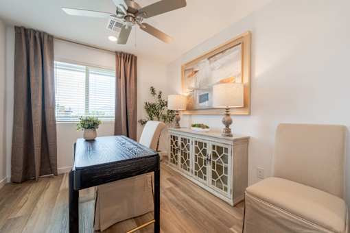 A room with a table, chairs, and a ceiling fan.