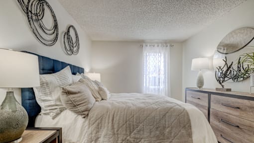 A bedroom with a bed, nightstand, and wall decor.