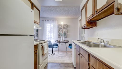 A kitchen with a white refrigerator and wooden cabinets.
