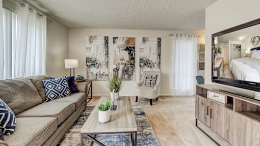 A living room with a couch, a coffee table, and a mirror.