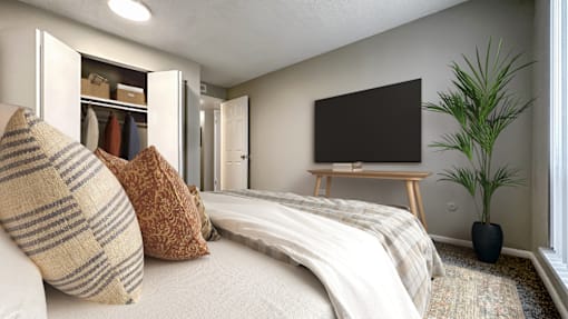 A bedroom with a bed, a television, and a plant.