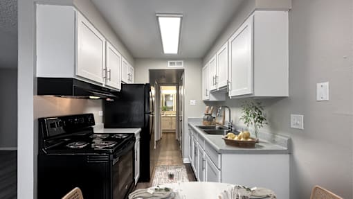 A kitchen with a black stove top oven and white cabinets.
