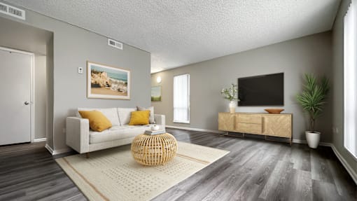 A living room with a white couch, a wicker table, and a painting on the wall.