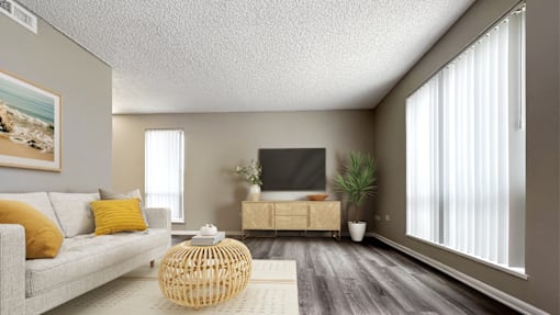 A living room with a grey couch, a wooden coffee table, a flat screen TV, and a potted plant.