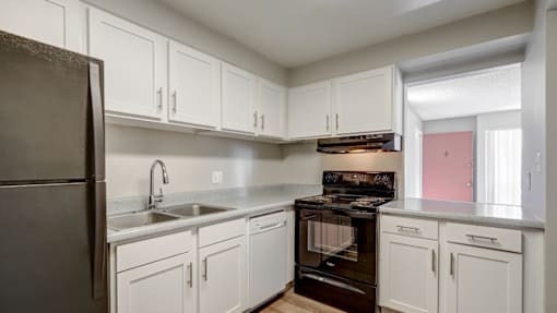 A kitchen with white cabinets and a black refrigerator.