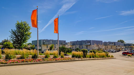 Two orange flags on a pole in front of a building.
