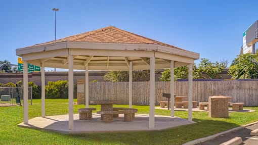 A pavilion with a red roof and a wooden bench in front of it.