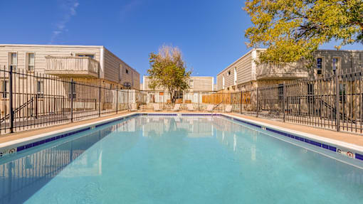 A swimming pool in a sunny day surrounded by a fence.