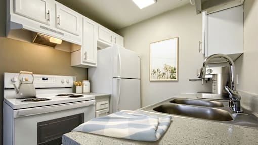 A kitchen with a stove, oven, refrigerator, and sink.